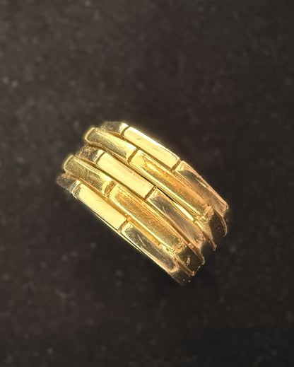 Angled overhead view of chunky 18k two-tone gold ridged band with polished geometric segments