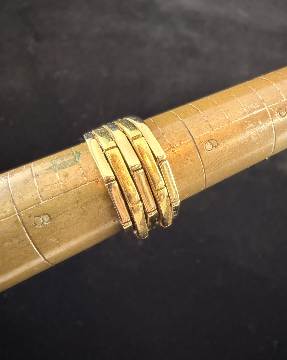 Close-up of 18k yellow and white gold ridged band ring shown on a ring mandrel, highlighting the alternating gold segments and geometric raised design